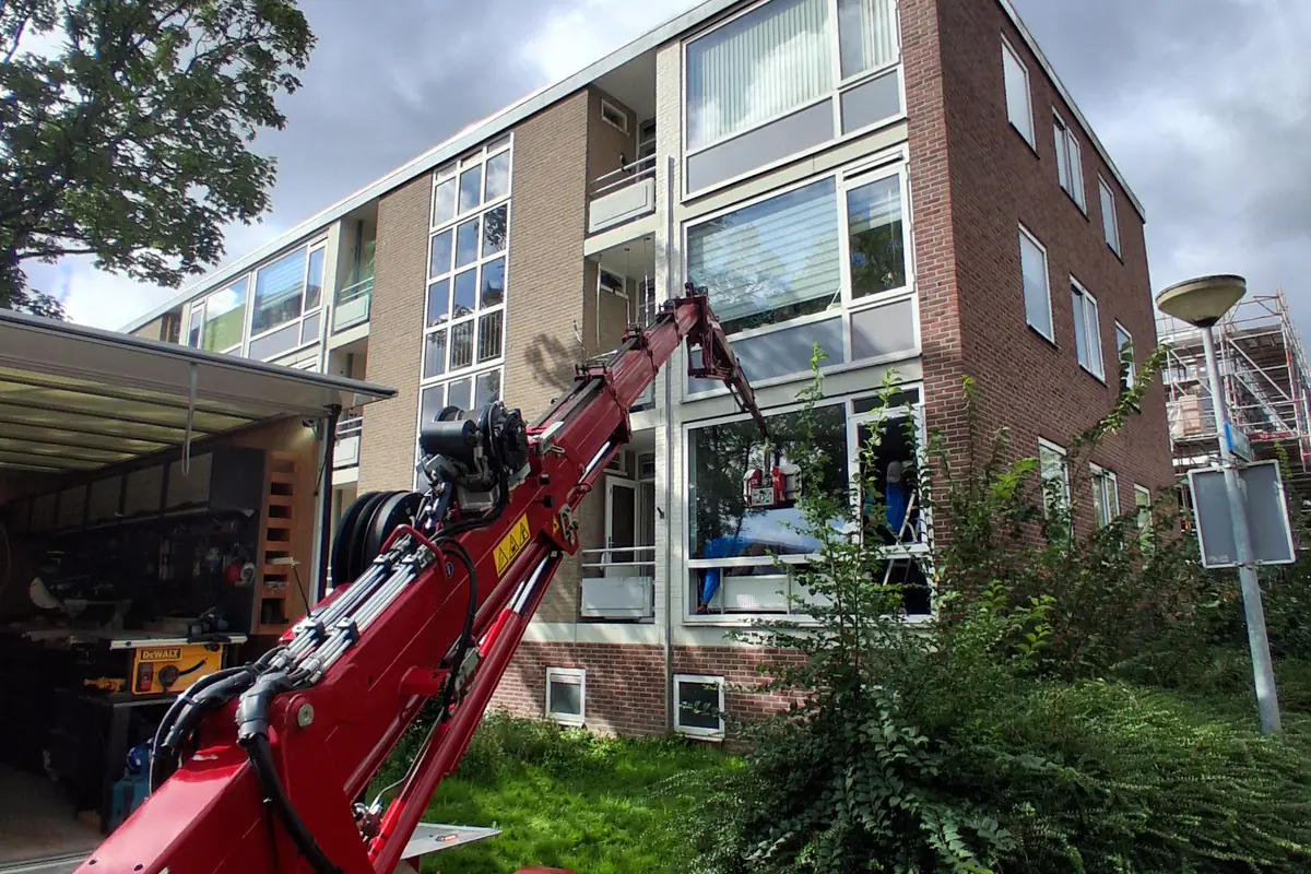 Kunststof kozijn wordt met een kraan geplaatst bij een appartementengebouw